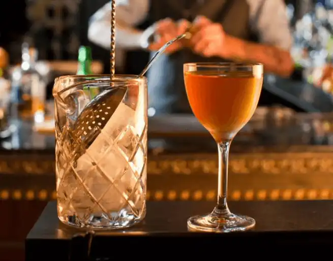 A glass full of ice-cube and another glass full of wine lying on the counter table