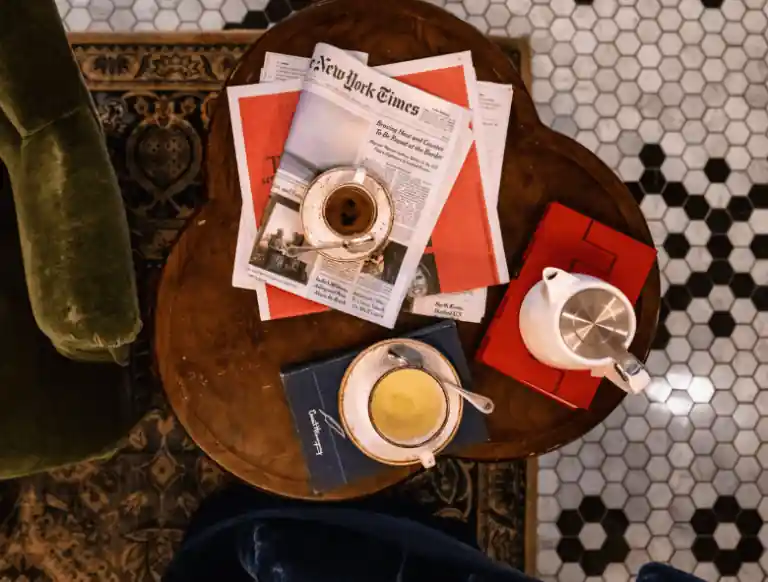 Two coffee cup-plate and a milk kettle with newspaper lying on the table
